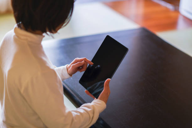 istock Japanese middle aged woman looking at tablet device 1296327671