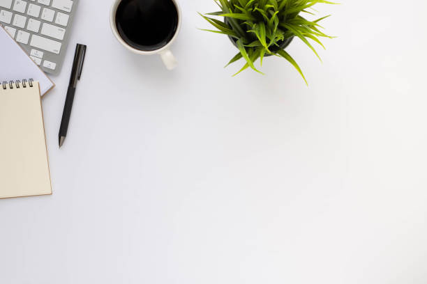 istock Top view above of White office desk table with keyboard, notebook and coffee cup with equipment office supplies. Business and finance concept. Workplace, Flat lay with blank copy space. 1296328034