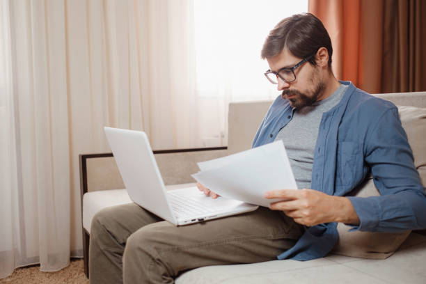 istock Entrepreneur works with a laptop and keeps a document in a home office 1296329675