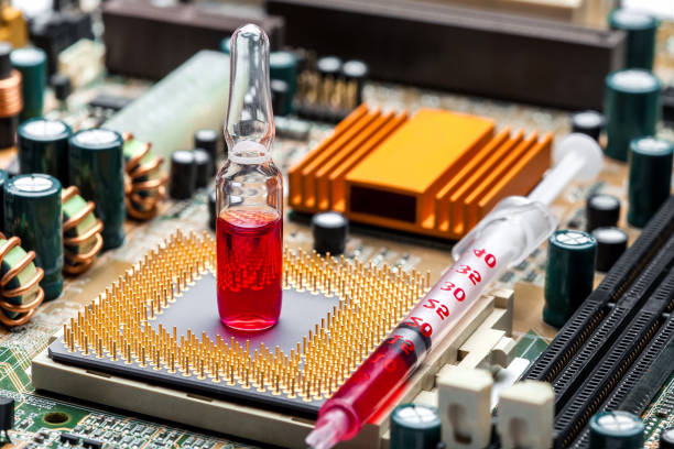 istock glass ampoule with red medicine with syringe on socket with cpu chip with contact legs on motherboard with microelectronic components, closeup on theme of cybernetics and implantation chipization. 1296329726