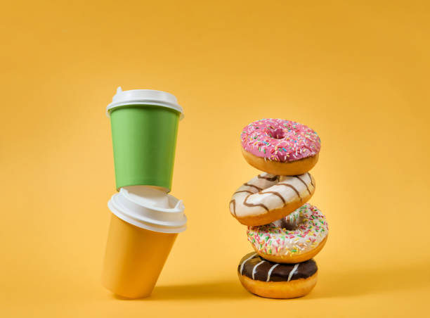 istock Two paper cups and several donuts on a yellow background 1296330924