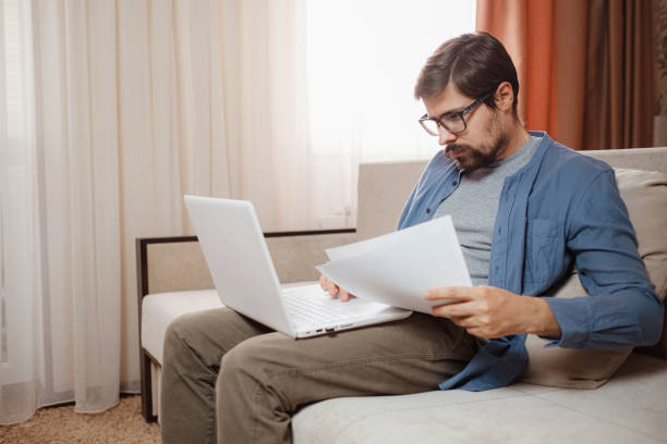 istock Entrepreneur works with a laptop and keeps a document in a home office 1296331241