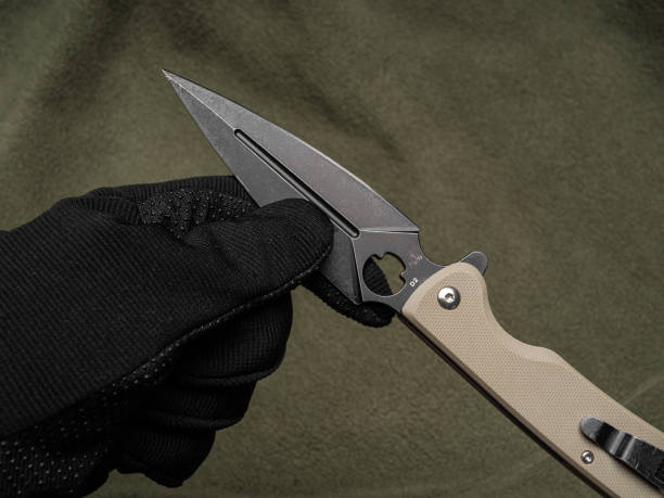 istock Hand in a black glove holds a pocket knife with a black blade 1296331315
