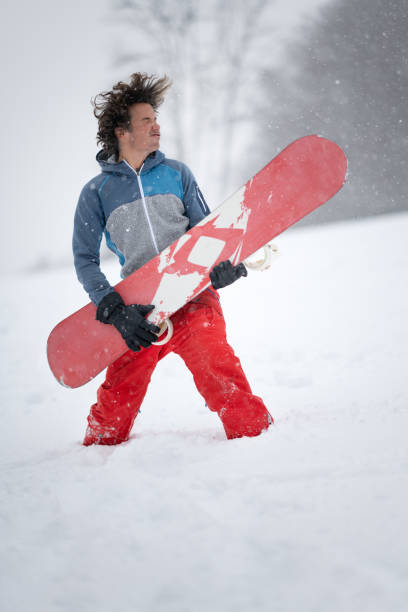 mann spielt luftgitarre im tiefschnee auf seinem snowboard in einem blizzard - snowboard extreme sports speed motion stock-fotos und bilder