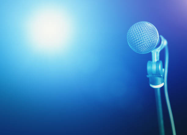 istock Speaker or singer's microphone under spotlights on a theater or lecture hall stage 1296332496