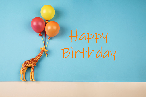 Giraffe toys holding balloons and text: Happy Birthday