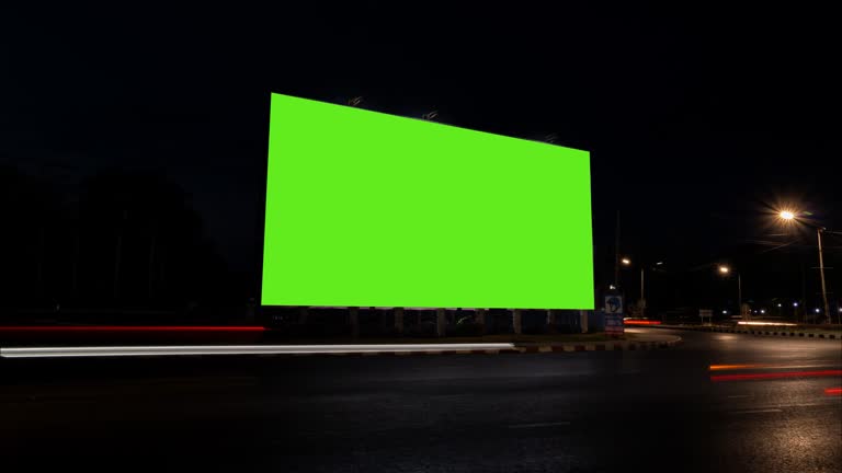 Time lapse of traffic at night with blank advertising billboard green screen.