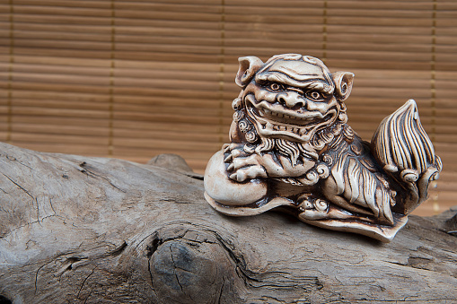 closeup of japanese netsuke figure on wooden and bamboo background. Statue lion mascot