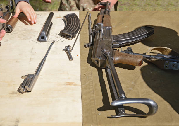 istock Old AK-47 machine guns with a folded butt and disassembled parts on the table. Exercise for disassembly and assembly of weapons 1296336207