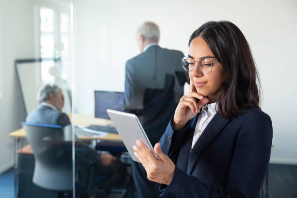 istock Pensive female manager in glasses looking on tablet screen 1296336578