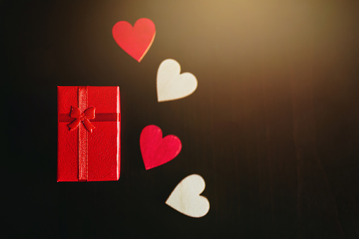 Red gift box and wooden hearts on a black background. Love concepts. Saint valentine background / wallpaper.