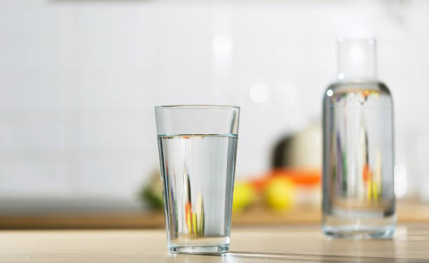 istock Glass of water is poured into a glass in a kitchen table 1296338152