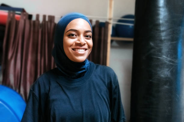 young smiling muslim sports woman with hijab indoors portrait of young smiling muslim sportswoman with hijab in the gym hijab photos stock pictures, royalty-free photos & images