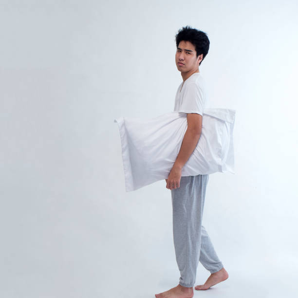 istock Sleepy young man with embracing pillow on white background 1296339641