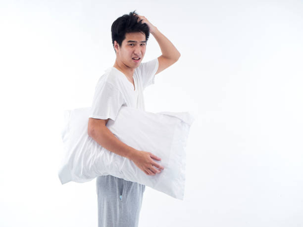 istock Sleepy young man with embracing pillow on white background 1296339643