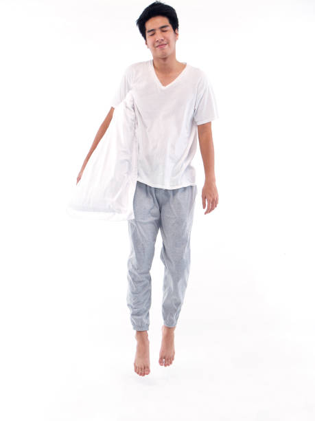 istock Young man in pajamas embracing pillow on white background 1296339651