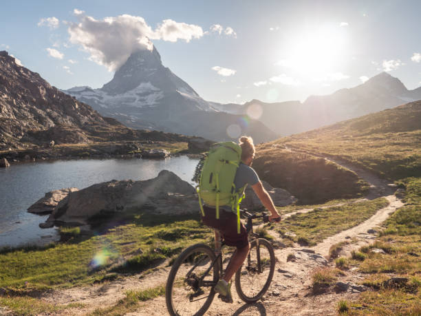 istock Man mountain biker rides along Lake below the Matterhorn mountain 1296341326