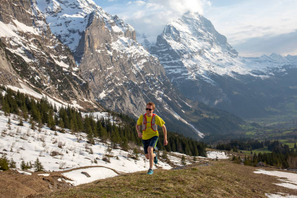 istock Mountain trail runner ascends grassy mountain ridge 1296341956