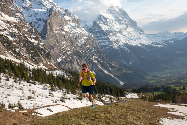 istock Mountain trail runner ascends grassy mountain ridge 1296342125