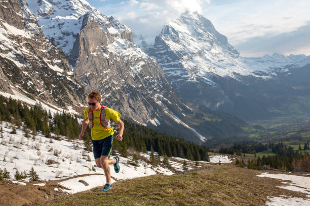 istock Mountain trail runner ascends grassy mountain ridge 1296342136