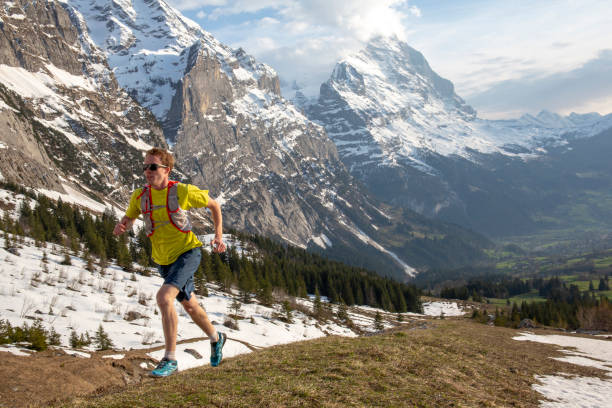 istock Mountain trail runner ascends grassy mountain ridge 1296342233