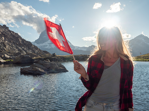 Female holding Swiss flag against the mountain landscape with the Matterhorn peak