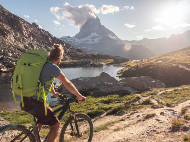 istock Man mountain biker rides along Lake below the Matterhorn mountain 1296342422
