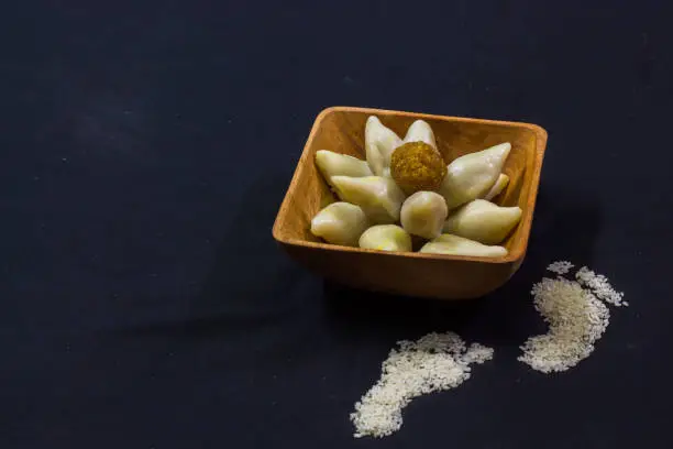 Photo of delicious bengali rice flour coconut dumpling served during bengali indian festival of makar sankranti. Photo taken in black background. copy space background for text.