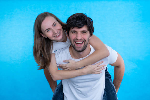 istock Image of a beautiful couple having fun while a man holds his girlfriend isolated on a blue background 1296346601