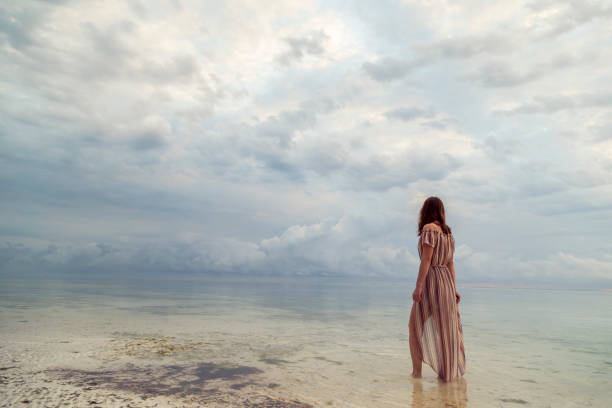 istock Woman walking down the beach at dawn 1296347149
