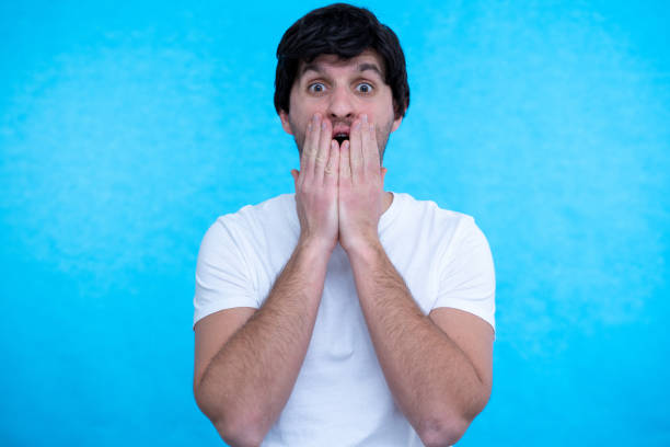 istock Portrait of amazed man over blue background 1296350144