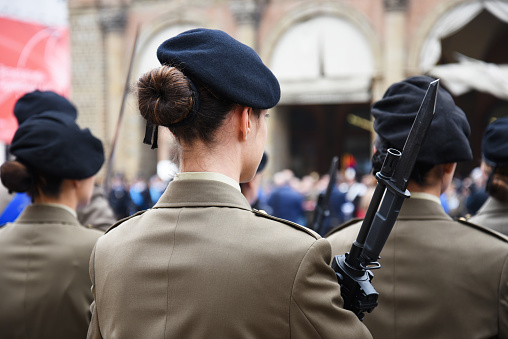 Bologna, Italy, November 04, 2018: Back view of military woman with a bayonet rifle - Detail with uniformed women standing for the military ceremony in the city - Concept of women's empowerment and armed defense of the Nation