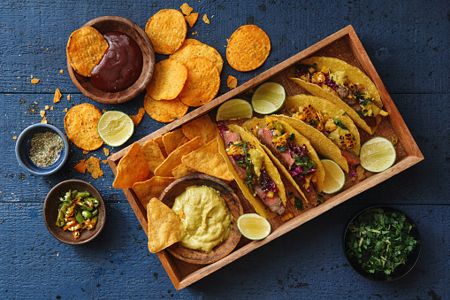 Mexican Crunchy Taco Shells with Beef and Vegetables. Nachos with guacamole. Flat lay top-down composition on wooden background.