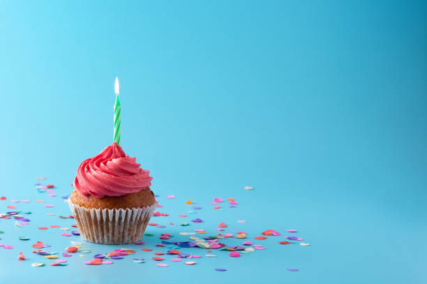 istock Pink birthday cupcake on blue background 1296352997