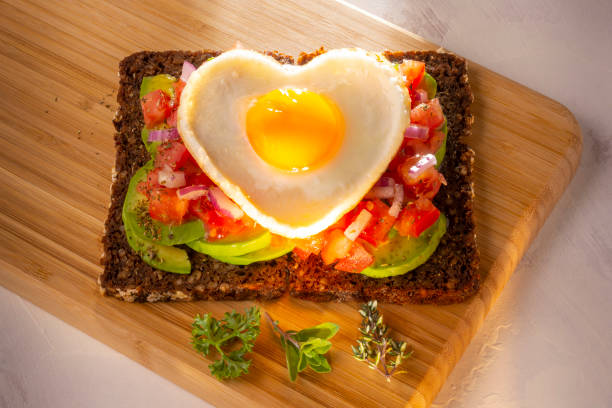 tostadas de centeno con huevo, tomate, aguacate - eggs breakfast heart shape fried egg fotografías e imágenes de stock