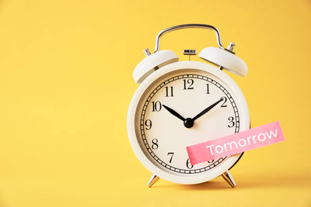 istock Procrastination, delay and postpone concept. Sticky note with word tomorrow on white alarm clock on yellow background. Urgency time 1296356660