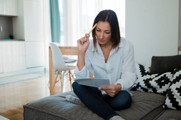 Worried woman reading document sitting at home Worried woman reading document eviction photos stock pictures, royalty-free photos & images