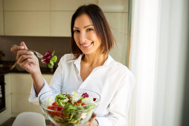 istock Young woman eating salad 1296356757