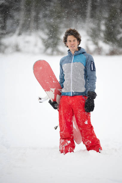 istock Man standing in fresh deep powder snow holding his Snowboard in a Blizzard 1296356780
