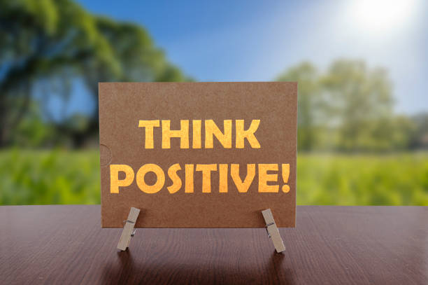 istock Think positive text on card on the table with sunny green park background. 1296357874