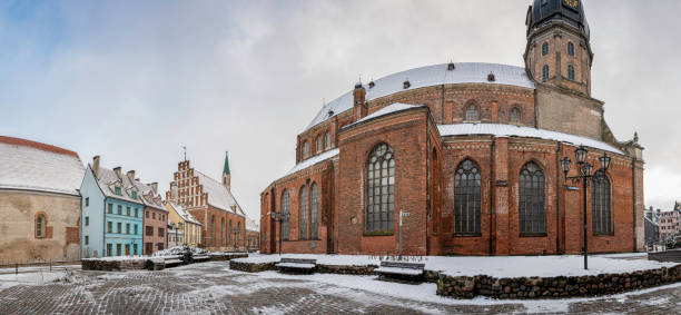 панорамный вид на церковь святого петра и окруженные исторические здания зимой в старом городе в риге, латвия - st peters basilica стоковые фото и изображения