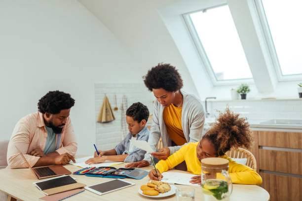 istock Two afro children and their parents doing homework together while sitting at the table 1296358120