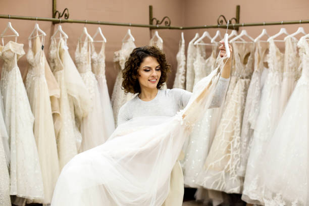 Young woman looking at wedding dresses Young woman choosing a wedding dress in a bridal shop. About 25 years old, Caucasian brunette. bridal boutique stock pictures, royalty-free photos & images