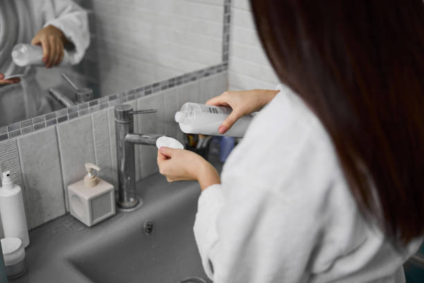 istock Woman in bathrobe using face cleanser indoors 1296361504