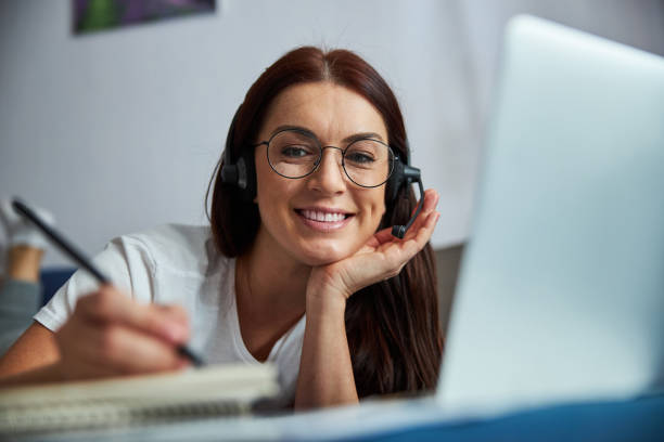istock Cheerful female making notes during online conference indoors 1296361612