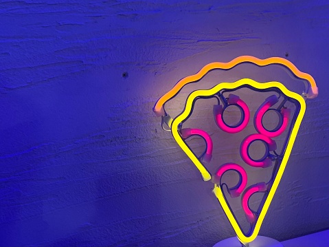 a piece of pizza shaped vivid colored lights with blue light background