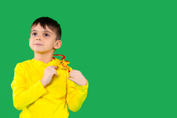 portrait of a boy with a lizard on his shoulder looking to the side against a green background with an empty side space. - iguana reptile smiling human face imagens e fotografias de stock