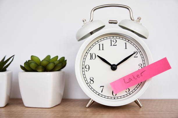 istock Procrastination and delay concept. Sticky note with word later on white alarm clock. Urgency time 1296367803