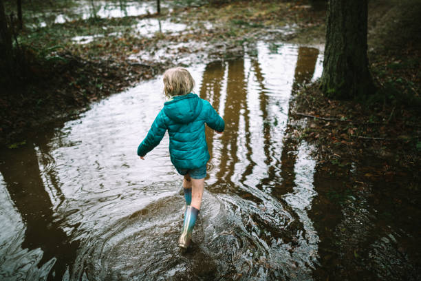 istock Girl Plays in Puddles From Heavy Rainfall 1296367904
