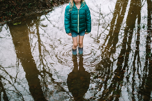 An elementary aged girl explores large pools of water accumulated from rain in Washington state, USA.